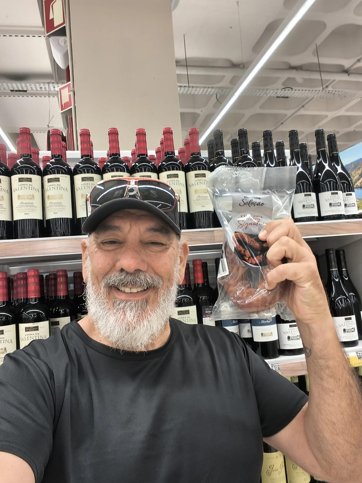 Nelson Viegas num corredor de vinhos de um hipermercado, com um chouriço na mão